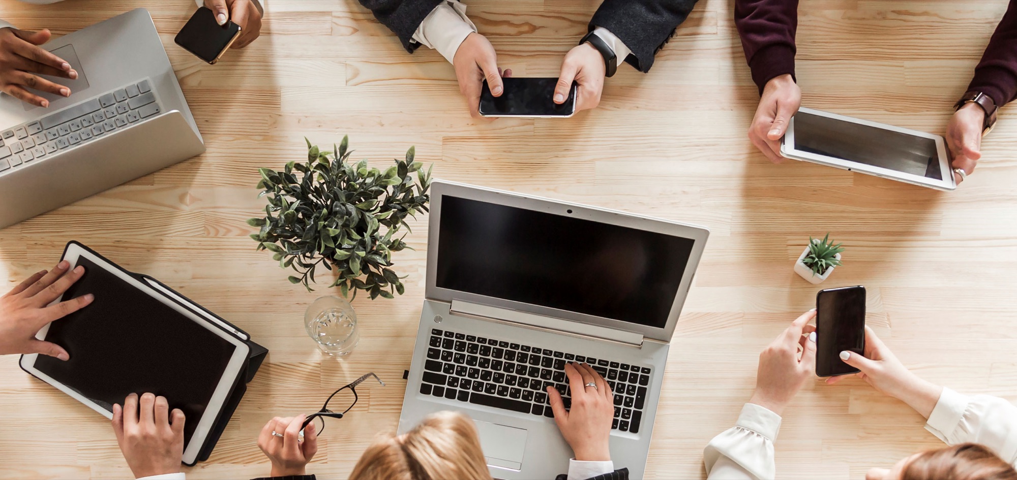 Team working together around a table with laptops and tablets